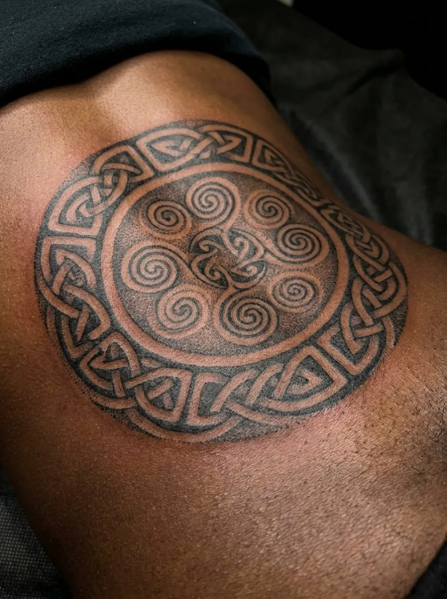 Tatouage frais de mandala celtique en dotwork noir couvrant les lombes, avec entrelacs et spirales en dégradés de points précis sur peau foncée